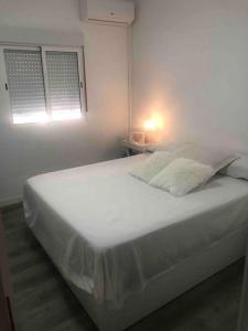 a white bed in a white room with a window at Gran apartamento en el centro in Almería