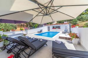 a patio with an umbrella and a swimming pool at Apartments Villa Nea Leona in Trogir