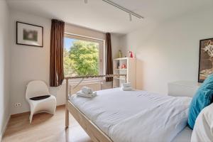 a bedroom with a bed and a chair and a window at Villa Stuifduin in Oostduinkerke