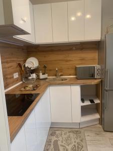 uma cozinha com armários brancos, um lavatório e um frigorífico em Квартал em Khmelʼnytsʼkyy