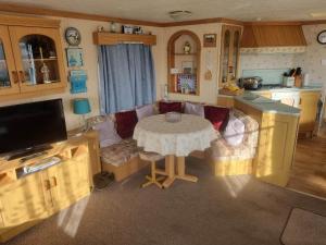 a living room with a table and a kitchen at Tm8 6 BERTH 2 BEDROOM CARAVAN P in Chapel Saint Leonards