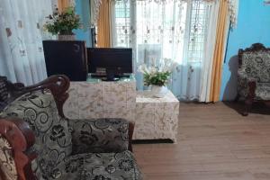 sala de estar con TV, silla y mesa en OYO 91477 Fazira Home Stay Syariah, en Halangan
