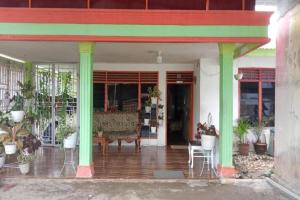 a porch with green columns and a table with plants at OYO 91477 Fazira Home Stay Syariah in Halangan