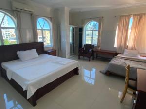 1 Schlafzimmer mit 2 Betten, einem Stuhl und Fenstern in der Unterkunft Old Durbar Skybar & Hotel in Phnom Penh