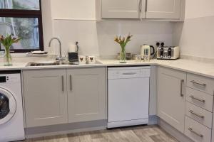 Una cocina blanca con fregadero y lavavajillas. en The Portpatrick Pad - A cosy 3 bed cottage, w. sea views & garden office, en Portpatrick