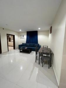 uma sala de estar com um sofá azul e uma mesa em قصر الجادل للشقق الفندقية em Ahad Rafidah