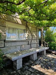 un banco de piedra sentado frente a una casa en Casa Suricato, en San Vicente do Mar