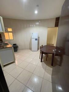uma cozinha com uma mesa e um frigorífico em قصر الجادل للشقق الفندقية em Ahad Rafidah