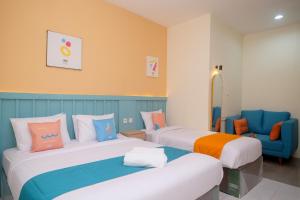Pokój hotelowy z 2 łóżkami i krzesłem w obiekcie Sans Hotel City Inn Solo by RedDoorz w mieście Surakarta