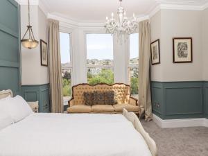 sypialnia z łóżkiem, żyrandolem i oknem w obiekcie Bradley House w mieście Ilfracombe