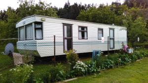 an old white trailer parked in a garden at Mobilhome Camping Paradijs in Zlatá Koruna
