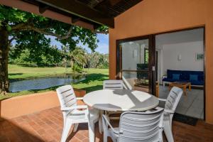 een witte tafel en stoelen op een patio met een zwembad bij San Lameer Villa 3303 - 2 Bedroom Classic - 4 pax - San Lameer Rental Agency in Southbroom