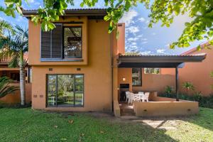 een huis met een patio en stoelen ervoor bij San Lameer Villa 3303 - 2 Bedroom Classic - 4 pax - San Lameer Rental Agency in Southbroom