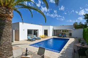 a villa with a swimming pool and a palm tree at Mercedes in Jávea