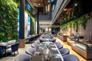 um restaurante com mesas longas, cadeiras e plantas em Mercure Tangerang Centre em Tangerang