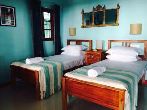 two beds in a room with blue walls at Majo House in Cherai Beach