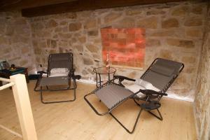 twee stoelen en een tafel in een kamer met een stenen muur bij Wellness House Plzeň - Božkov in Božkov