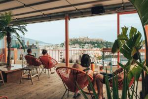 um grupo de pessoas sentadas em cadeiras numa varanda em Selina Athens Theatrou em Atenas