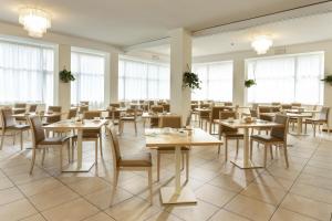 uma sala de jantar com mesas, cadeiras e janelas em Hotel Bikini em Rimini