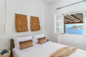 a white bedroom with a bed and a window at Calma Beach House in Elia Beach