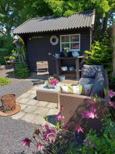 a garden with a couch in front of a shed at B&B Geniet Nátuurlijk in Wapserveen