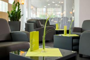 uma sala de espera com cadeiras e uma mesa com um vaso em Essential by Dorint Köln-Junkersdorf em Colônia