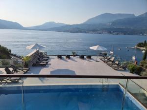 a swimming pool with chairs and a view of the water at Agape Rose Hotel in Tivat