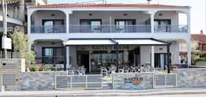 a restaurant with tables and chairs in front of a building at Nautico Rooms in Keramoti