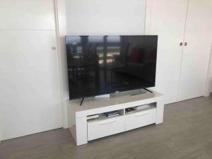 a white entertainment center with a flat screen tv at PRIMERA LÍNEA DE PLAYA, LA ARENA A TUS PIES in Aguadulce