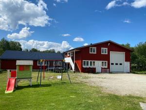 um celeiro vermelho com um parque infantil em frente em Leilighet Sølendet, i Brekken ved Røros em Røros