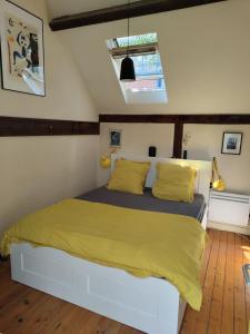 una camera da letto con un grande letto con lenzuola gialle di Atelier d'artiste - Loft with garden center of Paris a Parigi