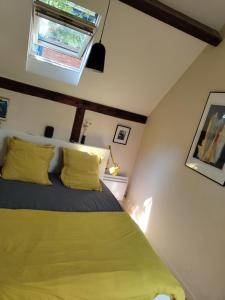 Un dormitorio con una cama con almohadas amarillas y una ventana en Atelier d'artiste - Loft with garden center of Paris en París