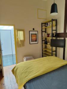 um quarto com uma cama com um cobertor amarelo em Atelier d'artiste - Loft with garden center of Paris em Paris