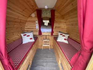 Habitación con 2 camas en una cabaña de madera con cortinas rojas en Andrella Auszeithof - Schlaferlebnis im Holzfass en Friedersbach