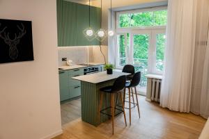 eine Küche mit grünen Schränken und einem Tisch mit Hockern in der Unterkunft Meridiano apartamentai in Klaipėda