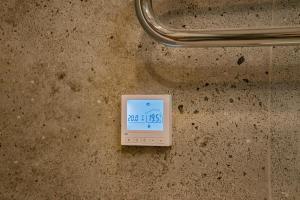 eine digitale Uhr an der Wand eines Badezimmers in der Unterkunft Meridiano apartamentai in Klaipėda + 11 Fotos