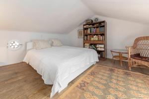 a bedroom with a white bed and a book shelf at Šentjane bay view house in Portorož
