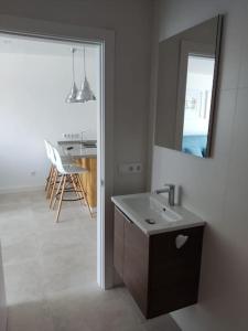 een witte badkamer met een wastafel en een spiegel bij Villa Cariño - Apartamento en Malpica de Bergantiños in Malpica