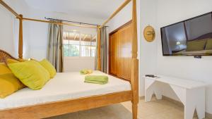 Chalet Mar في كاليتا ذي فوستي: غرفة نوم بسرير مع وسائد صفراء وتلفزيون