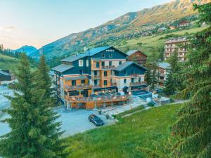 - une vue aérienne sur une grande maison dans une montagne dans l'établissement Hôtel 16 | 150 Montagne & Spa Nuxe, à Vars