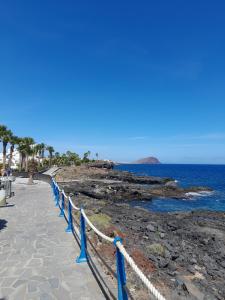 a walkway next to the ocean with blue barriers at Los Abrigos oceano al alba wifi in Los Abrigos