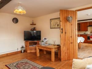 un salon avec une télévision et une table en bois dans l'établissement Northwood Barn, à Okehampton