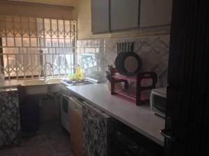 eine Küche mit einem Waschbecken und einer Theke mit einem Spiegel in der Unterkunft Charming 2-Bed Cottage in Benin City in Benin-Stadt