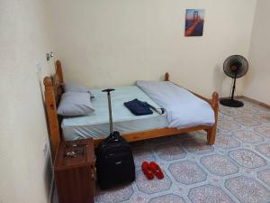 a bedroom with a bed with a suitcase and red shoes at Charming 2-Bed Cottage in Benin City in Benin City