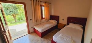 um quarto com 2 camas e uma porta de vidro deslizante em Resort Te Zagolli em Orikum