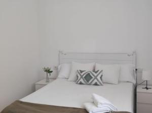 een witte slaapkamer met een groot wit bed met witte kussens bij Casa Dina II. in Carballino