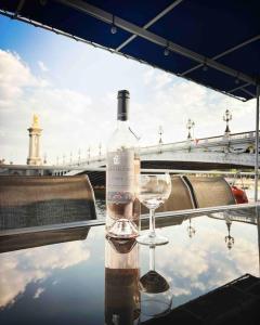- une bouteille de vin et un verre assis sur une table dans l'établissement Péniche de charme au pont Alexandre III, à Paris