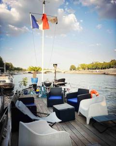 łódź z krzesłami i flagą na tarasie w obiekcie Péniche de charme au pont Alexandre III w Paryżu