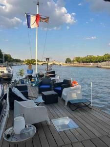drewniana przystań z krzesłami i flagą na łodzi w obiekcie Péniche de charme au pont Alexandre III w Paryżu