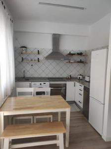 een keuken met een houten tafel en witte apparaten bij Casa Dina II. in Carballino